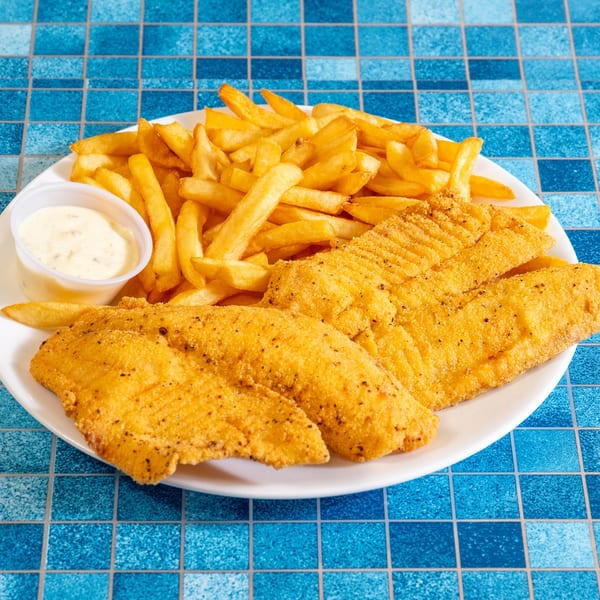 Fried fish fillets and golden french fries with tartar sauce on a white plate.