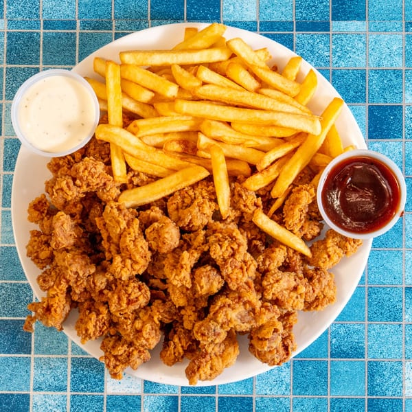 A plate of 4 Brothers Chicken & Fish fried chicken pieces and french fries with two dipping sauces.