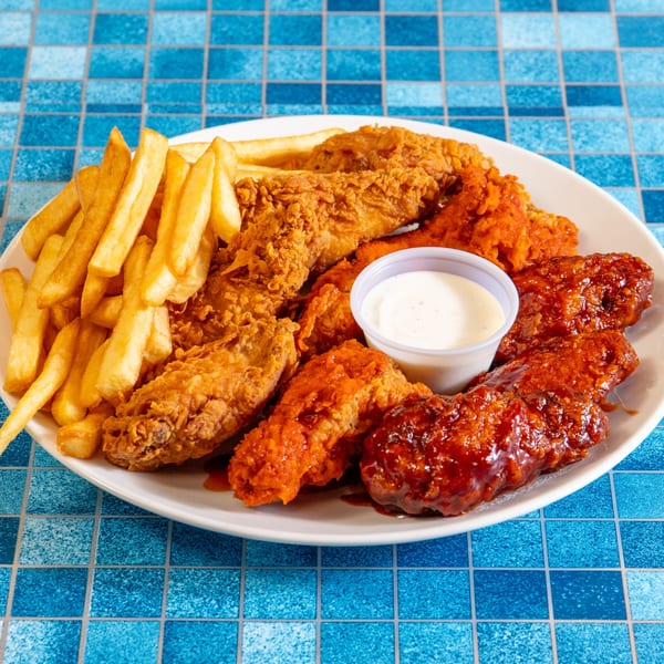 A white plate with fried chicken tenders, french fries, and a side of ranch dressing.